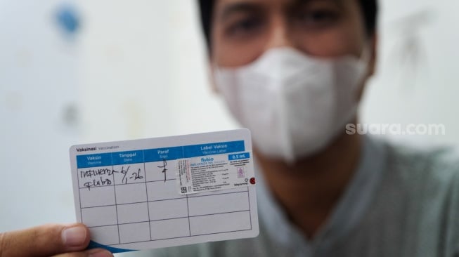 Pasien menunjukan kartu vaksinasi di Klinik Pratama Dermaga Raya, Jakarta, Rabu (7/1/2026). [Suara.com/Alfian Winanto]