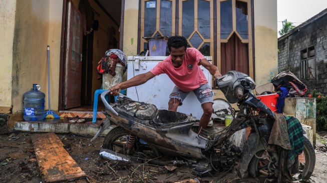 Seorang warga mengamankan sepeda motor yang rusak pascabanjir di Desa Tongute Ternate asal Kabupaten Halmahera Barat, Maluku Utara, Kamis (8/1/2026). [ANTARA FOTO/Andri Saputra/tom]
