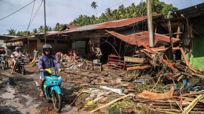 Pengendara sepeda motor melintas di depan rumah warga yang rusak pascabanjir di Desa Tongute Ternate asal Kabupaten Halmahera Barat, Maluku Utara, Kamis (8/1/2026). [ANTARA FOTO/Andri Saputra/tom]