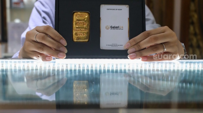 Pramuniaga menunjukkan emas batangan di sebuah gerai Galeri 24, Jakarta, Jumat (9/1/2026). [Suara.com/Alfian Winanto]