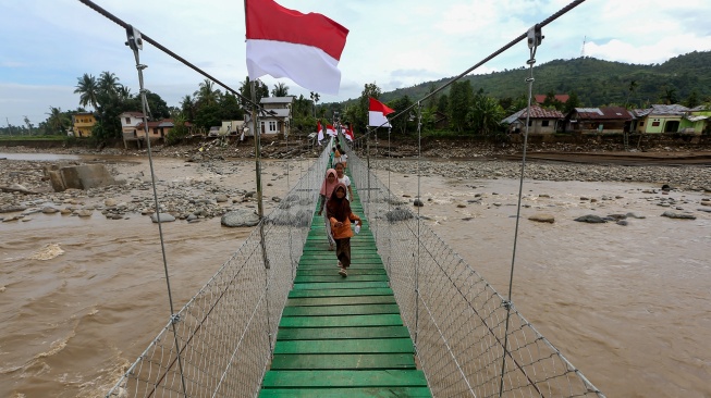 Pelajar melintas di atas jembatan gantung yang baru selesai pembangunannya di Meureudu, Pidie Jaya, Aceh, Jumat (9/1/2026). [ANTARA FOTO/Irwansyah Putra/bar] 