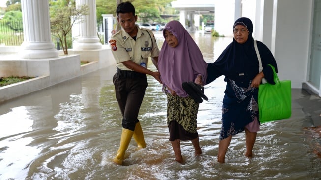 Satpam membantu warga melintasi banjir di RSUD Kota Serang, Banten, Senin (12/1/2026). [ANTARA FOTO/Muhammad Bagus Khoirunas/nz]