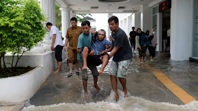 Warga menggotong pasien saat banjir di RSUD Kota Serang, Banten, Senin (12/1/2026). [ANTARA FOTO/Muhammad Bagus Khoirunas/nz]