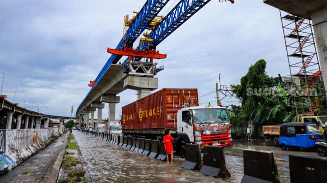 Kendaraan truk melewati banjir yang menggenang di Jalan RE Martadinata, Tanjung Priok, Jakarta, Senin (12/1/2026). [Suara.com/Alfian Winanto]