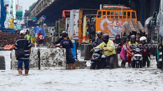 Pengendara melewati banjir yang menggenang di Jalan RE Martadinata, Tanjung Priok, Jakarta, Senin (12/1/2026). [Suara.com/Alfian Winanto]