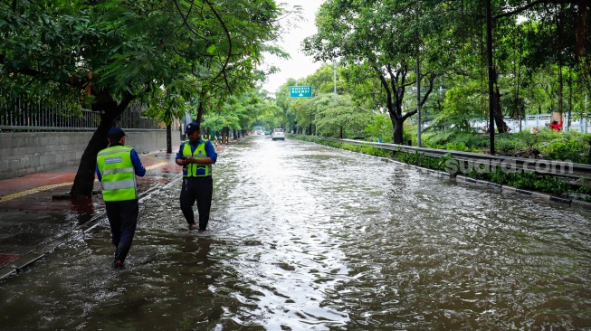 Petugas mengatur lalu lintas saat banjir menggenang di Jalan Danau Sunter Raya, Jakarta, Senin (12/1/2026). [Suara.com/Alfian Winanto]