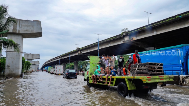 Kendaraan truk melewati banjir yang menggenang di Jalan RE Martadinata, Tanjung Priok, Jakarta, Senin (12/1/2026). [Suara.com/Alfian Winanto]