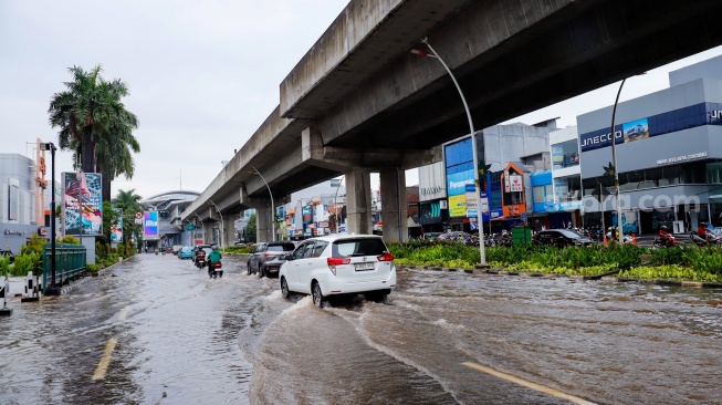 Pengendara melewati banjir yang menggenang di Jalan Boulevard Raya, Kelapa Gading, Jakarta, Senin (12/1/2026). [Suara.com/Alfian Winanto]
