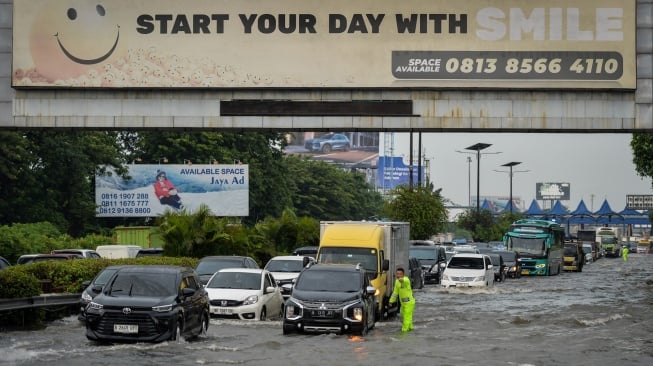 Polisi mengatur lalu lintas kendaraan saat banjir di Jalan Tol Sedyatmo, Kota Tangerang, Banten, Senin (12/1/2026). [ANTARA FOTO/Putra M. Akbar/nz]