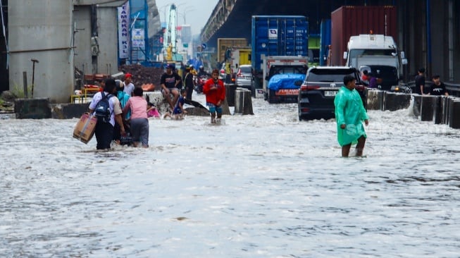 Pengendara melewati banjir yang menggenang di Jalan RE Martadinata, Tanjung Priok, Jakarta, Senin (12/1/2026). [Suara.com/Alfian Winanto]