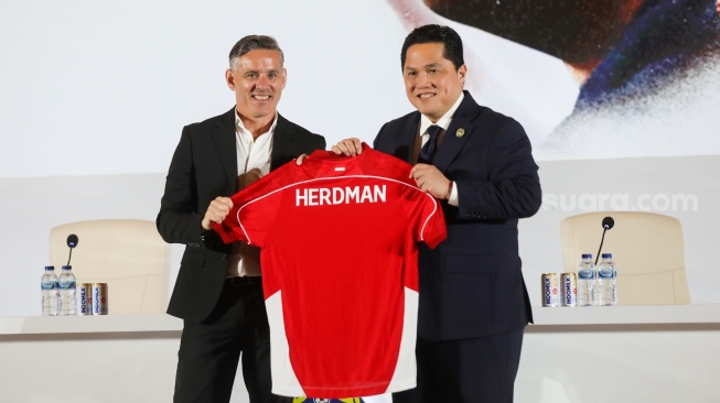 Ketum PSSI Erick Thohir (kanan) memberikan jersey pada Pelatih Timnas Indonesia John Herdman (kiri) pada acara perkenalan pelatih baru Timnas Indonesia di Jakarta, Selasa (13/1/2026). [Suara.com/Alfian Winanto]