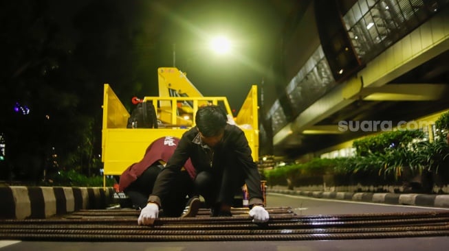 Petugas merapikan besi tiang monorel usai dibongkar di Jalan H. R. Rasuna Said, Jakarta, Rabu (14/1/2026). [Suara.com/Alfian Winanto]