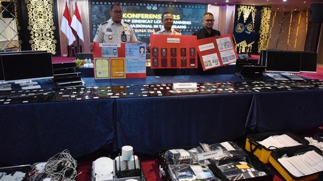 Plt. Dirjen Imigrasi Yuldi Yusman (tengah) didampingi Kasubdit Pengawasan Keimigrasian Arief Eka Riyanto (kiri) dan Koordinator Fungsi Komunikasi Publik Ditjen Imigrasi Achmad Nur Saleh (kanan) menunjukkan barang bukti dalam konferensi pers pengungkapan sindikat Love Scamming internasional di Kantor Direktorat Jenderal Imigrasi Kementerian Imigrasi dan Pemasyarakatan, Jakarta, Senin (19/1/2026). [ANTARA FOTO/Indrianto Eko Suwarso/wsj]