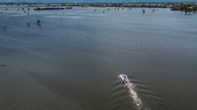 Warga menggunakan perahu bermesin untuk menyeberangi akses jalan darat yang terendam banjir di Desa Mejobo, Kudus, Jawa Tengah, Senin (19/1/2026). [ANTARA FOTO/Aprillio Akbar/rwa]

