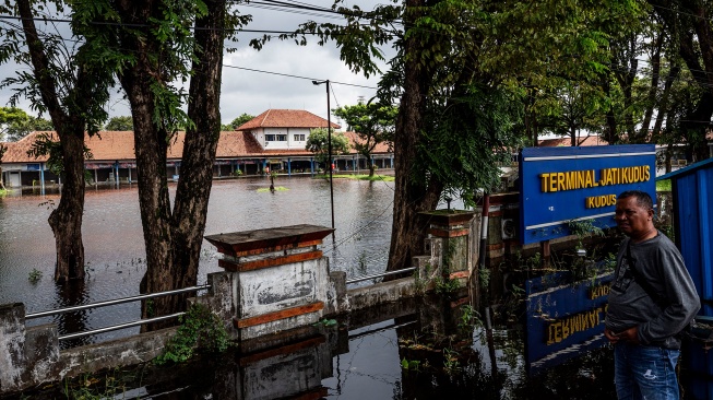 Warga berdiri di depan Terminal Induk Bus Antar Kota Jati Kudus yang terendam banjir di Kudus, Jawa Tengah, Senin (19/1/2026). [ANTARA FOTO/Aprillio Akbar/rwa]