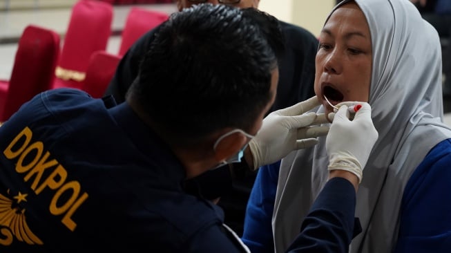 Petugas mengambil sampel air liur keluarga korban Pesawat ATR 42-500 di Pos Antemortem DVI Biddokkes Polda Sulsel, Makassar, Sulawesi Selatan, Senin (19/1/2026). [ANTARA FOTO/Arnas Padda/wsj]