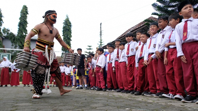Relawan Satuan Pelayanan Pemenuhan Gizi (SPPG) Danupayan berpakaian seni Warokan saat mendistribusikan makan bergizi gratis (MBG) ke SD Negeri Pandemulyo di Bulu, Temanggung, Jawa Tengah, Senin (19/1/2026). [ANTARA FOTO/Anis Efizudin/wsj] 