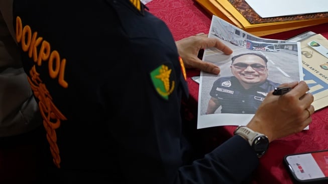 Petugas menerima foto dari keluarga korban Pesawat ATR 42-500 di Pos Antemortem DVI Biddokkes Polda Sulsel, Makassar, Sulawesi Selatan, Senin (19/1/2026). [ANTARA FOTO/Arnas Padda/wsj]