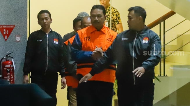 Wali Kota Madiun Maidi (tengah) dibawa ke mobil tahanan usai menjalani pemeriksaan di Gedung Merah Putih KPK, Jakarta, Selasa (20/1/2026). [Suara.com/Alfian Winanto]
