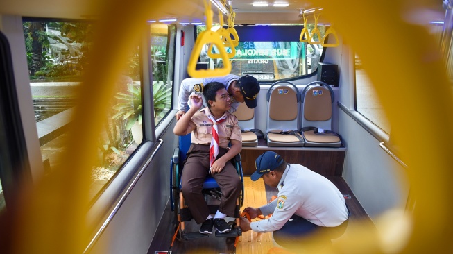 Petugas Dishub membantu memasang pengaman kursi roda bagi siswa penyandang disabilitas saat menaiki bus sekolah ramah disabilitas pada peluncuran armada tersebut di Pendopo Balai Kota, Jakarta, Rabu (21/1/2026). [ANTARA FOTO/Indrianto Eko Suwarso/bar]
