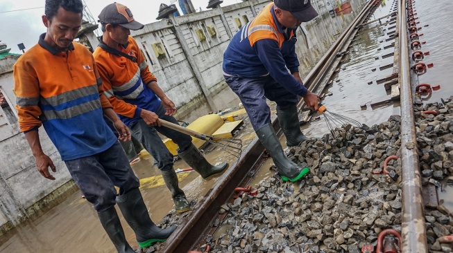 Sejumlah pekerja meratakan batu kricak (ballast) pada jalur rel kereta api yang terdampak banjir di sekitar Stasiun Pekalongan, Kota Pekalongan, Jawa Tengah, Rabu (21/1/2026). [ANTARA FOTO/Harviyan Perdana Putra/wsj]
