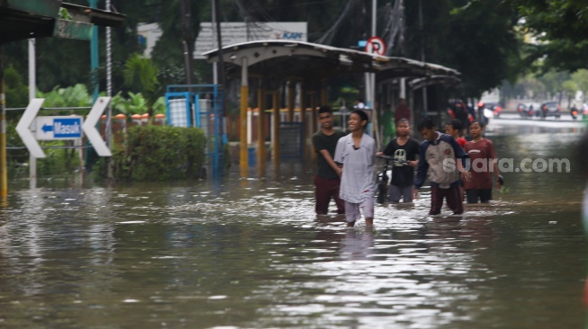 Warga beraktivitas di tengah genangan banjir yang merendam di sekitar Cempaka Putih, Jakarta, Kamis (22/1/2026). [Suara.com/Alfian Winanto]
