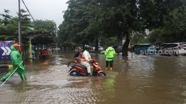 Warga beraktivitas di tengah genangan banjir yang merendam di sekitar Cempaka Putih, Jakarta, Kamis (22/1/2026). [Suara.com/Alfian Winanto]
