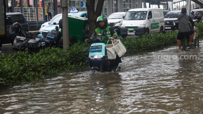 Warga beraktivitas di tengah genangan banjir yang merendam di sekitar Cempaka Putih, Jakarta, Kamis (22/1/2026). [Suara.com/Alfian Winanto]

