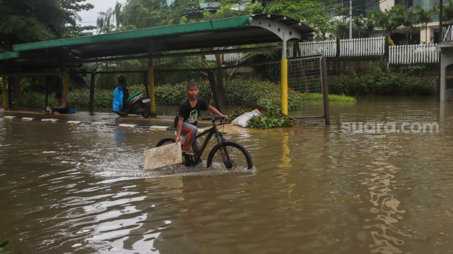 Warga beraktivitas di tengah genangan banjir yang merendam di sekitar Cempaka Putih, Jakarta, Kamis (22/1/2026). [Suara.com/Alfian Winanto]

