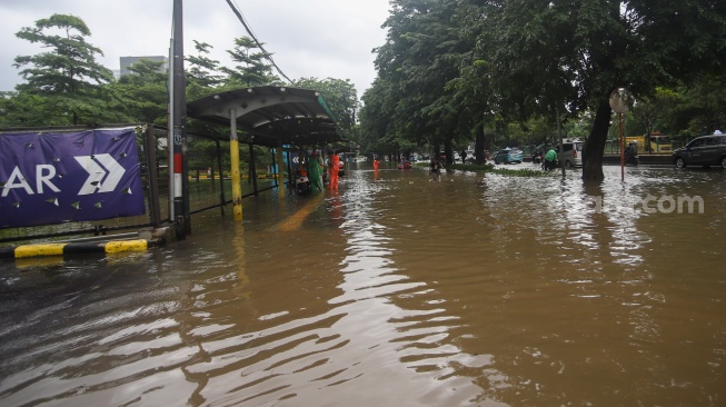 Warga beraktivitas di tengah genangan banjir yang merendam di sekitar Cempaka Putih, Jakarta, Kamis (22/1/2026). [Suara.com/Alfian Winanto]
