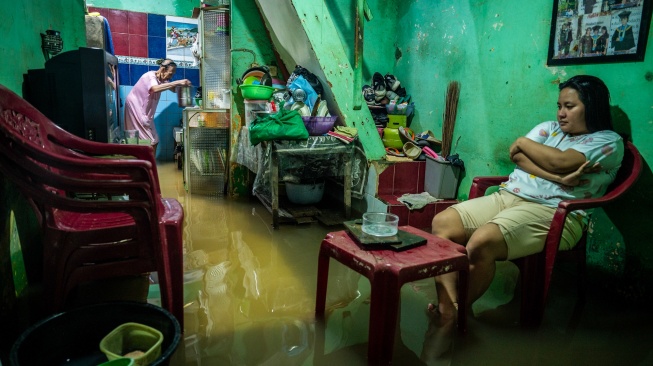Warga berada di rumah saat banjir merendam perkampungan di Kebon Pala, Jatinegara, Jakarta, Jumat (23/1/2026). [ANTARA FOTO/Bayu Pratama S/foc]
