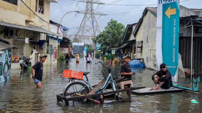 Warga berada di jalan yang terendam banjir di Jalan Outer Ring Road, Cengkareng, Jakarta, Jumat (23/1/2026). [ANTARA FOTO/Naufal Khoirulloh/foc]