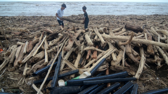 Sejumlah anak mengumpulkan kayu yang terdampar di Pantai Utara Desa Larangan, Kabupaten Tegal, Jawa Tengah, Senin (26/1/2026). [ANTARA FOTO/Oky Lukmansyah/foc]