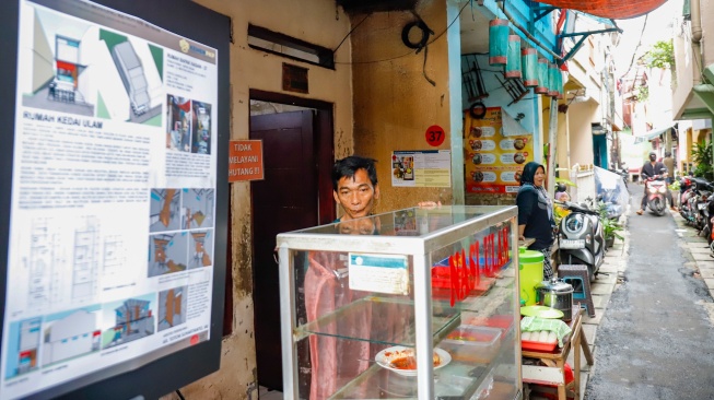 Warga berdiri di depan rumahnya yang sudah direnovasi di perkampungan padat penduduk, kawasan Menteng Tenggulun, Jakarta, Rabu (28/1/2026). [Suara.com/Alfian Winanto]