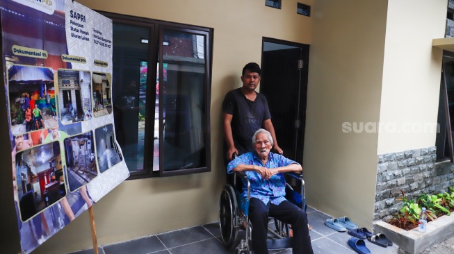 Warga berdiri di depan rumahnya yang sudah direnovasi di perkampungan padat penduduk, kawasan Menteng Tenggulun, Jakarta, Rabu (28/1/2026). [Suara.com/Alfian Winanto]