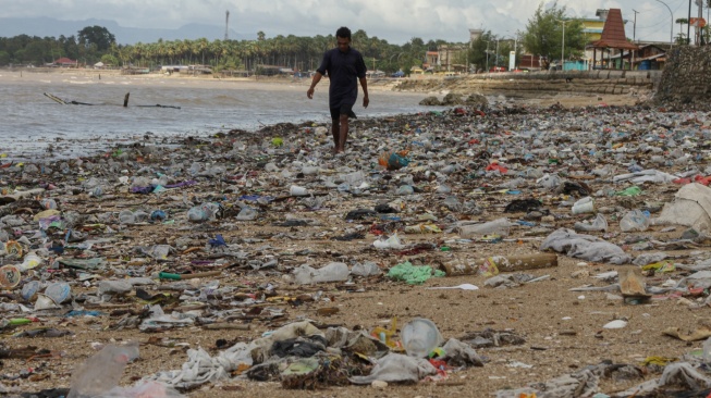 Seorang warga berjalan diatas tumpukan sampah di Pesisir Taman Wisata Laut Teluk Kupang, Kota Kupang, Nusa Tenggara Timur, Kamis (29/1/2026).  [ANTARA FOTO/Mega Tokan/bar]