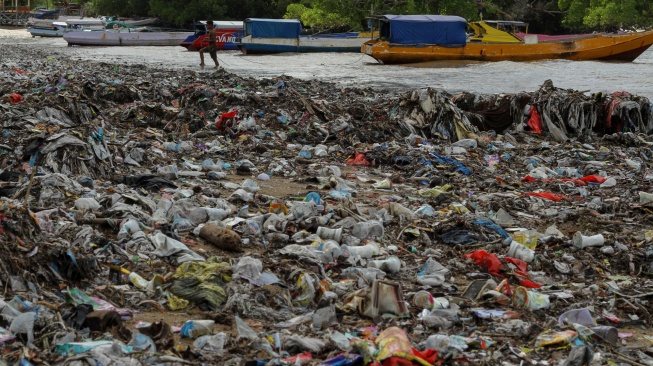 Seorang warga menarik tali perahu melewati tumpukan sampah di Pesisir Taman Wisata Laut Teluk Kupang, Kota Kupang, Nusa Tenggara Timur, Kamis (29/1/2026).  [ANTARA FOTO/Mega Tokan/bar]