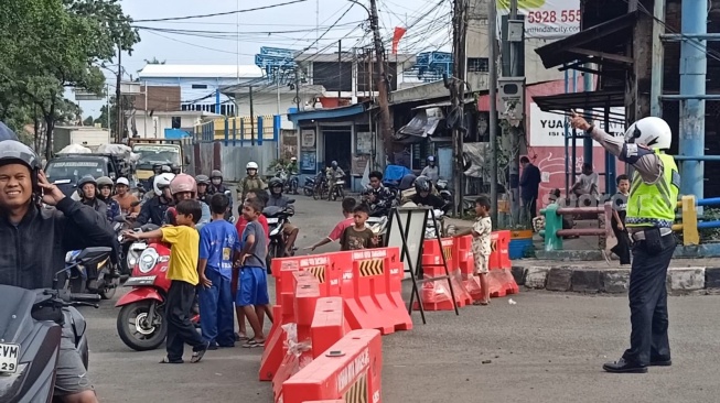 Anak-anak bantu polisi arahkan jalan di sekitar Pintu Air 10 Tangerang pada Jumat, 30 Januari 2026. [Suara.com/Rena Pangesti]