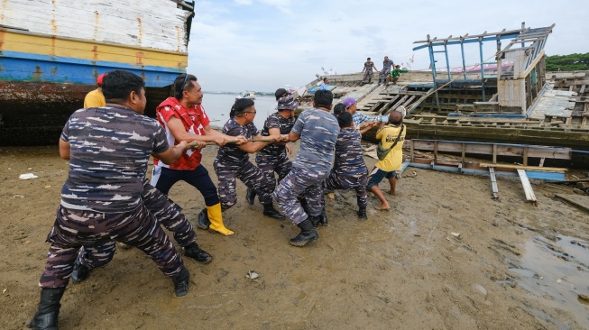 Personel TNI bersama warga bergotong royong menjatuhkan bangkai kapal di kawasan Kendari Beach, Kecamatan Kendari Barat, Kendari, Sulawesi Tenggara, Selasa (3/2/2026). [ANTARA FOTO/Andry Denisah/bar]