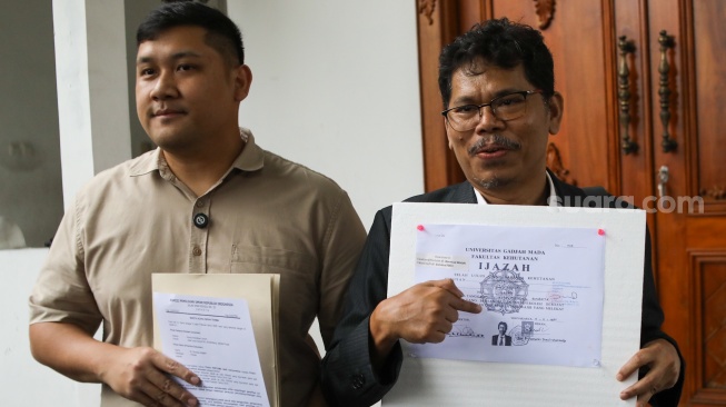 Pengamat Kebijakan Publik Bonatua Silalahi (kanan) menunjukan salinan asli ijazah Presiden ke-7 Joko Widodo di depan kantor KPU RI, Jakarta, Senin (9/2/2026). [Suara.com/Alfian Winanto]
