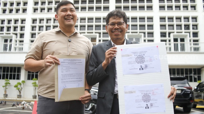 Pengamat Kebijakan Publik Bonatua Silalahi (kanan) menunjukan salinan asli ijazah Presiden ke-7 Joko Widodo di depan kantor KPU RI, Jakarta, Senin (9/2/2026). [Suara.com/Alfian Winanto]
