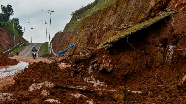 Warga melintasi jalan yang longsor di Jalur Lingkar Utara Jatigede, Kabupaten Sumedang, Jawa Barat, Jumat (13/2/2026).  [ANTARA FOTO/Raisan Al Farisi/nz]