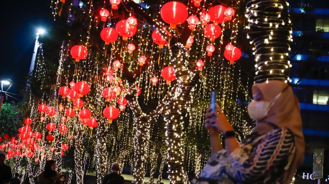 Warga melihat instalasi pencahayaan dalam Jakarta Light Festival edisi Imlek di kawasan Bundaran HI, Jakarta, Jumat (13/2/2026). [Suara.com/Alfian Winanto]
