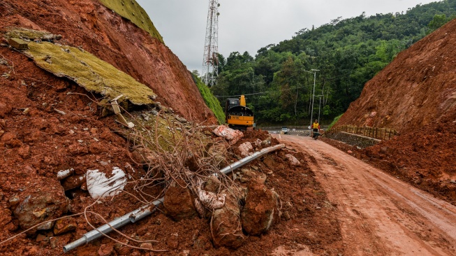 Warga melintasi jalan yang longsor di Jalur Lingkar Utara Jatigede, Kabupaten Sumedang, Jawa Barat, Jumat (13/2/2026). [ANTARA FOTO/Raisan Al Farisi/nz]