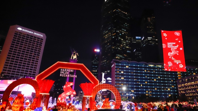Warga melihat instalasi pencahayaan dalam Jakarta Light Festival edisi Imlek di kawasan Bundaran HI, Jakarta, Jumat (13/2/2026). [Suara.com/Alfian Winanto]
