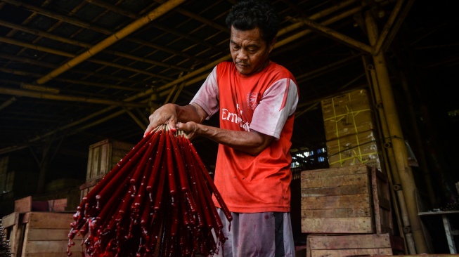 Pekerja mencelupkan hio ke dalam ember berisi cat di Kosambi, Kabupaten Tangerang, Banten, Jumat (13/2/2026). [ANTARA FOTO/Putra M. Akbar/nz]