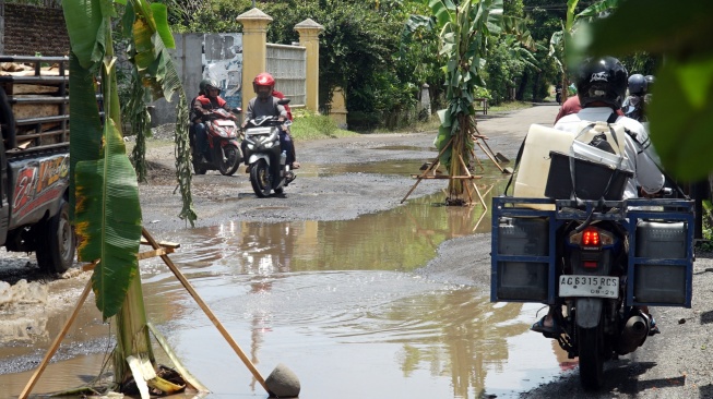 Pengendara melintasi jalan rusak yang sebagian ditanami pohon pisang oleh warga, di Jalan Raya Pandean, Ngunut, Tulungagung, Jawa Timur, Senin (16/2/2026). [ANTARA FOTO/Destyan Sujarwoko/rwa]