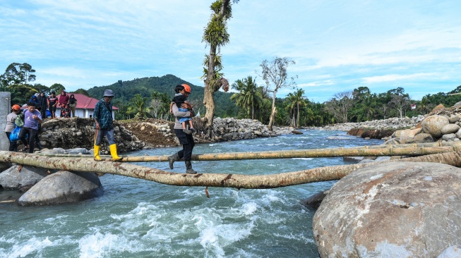 Polisi membantu penyintas bencana menyeberangi jembatan darurat di Jorong Kayu Pasak Selatan, Nagari Salareh Aia, Palembayan, Agam, Sumatera Barat, Rabu (18/2/2026). [ANTARA FOTO/Wahdi Septiawan/YU]