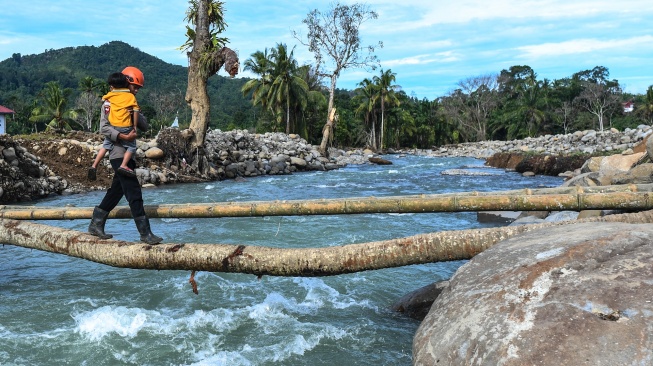 Polisi membantu penyintas bencana menyeberangi jembatan darurat di Jorong Kayu Pasak Selatan, Nagari Salareh Aia, Palembayan, Agam, Sumatera Barat, Rabu (18/2/2026). [ANTARA FOTO/Wahdi Septiawan/YU]