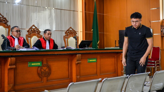 Tersangka dugaan kasus penghinaan terhadap Suku Sunda Muhammad Adimas Firdaus Putra Nasihan alias Resbob (kanan) berjalan menuju kursi saat menjalani sidang perdana di Pengadilan Negeri Bandung, Jawa Barat, Senin (23/2/2026). [ANTARA FOTO/Raisan Al Farisi/YU]